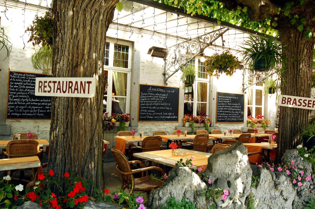 Terrasse extérieure du restaurant avec enseigne et plantes fleuries