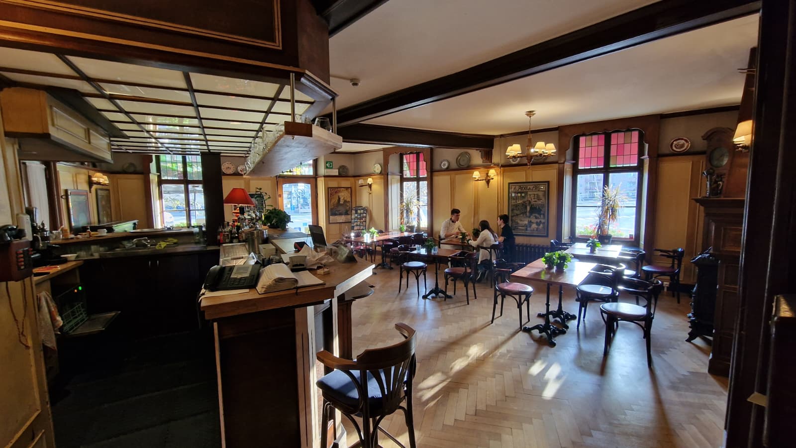 Bar-brasserie intérieur avec boiseries, parquet chevrons et vitraux colorés